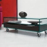 Glass coffee table with metal casters and dark wood drawers